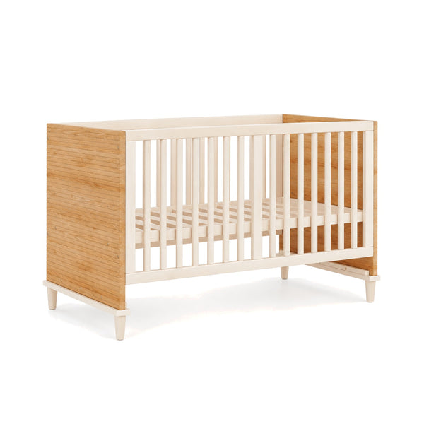 Lit bébé en bois naturel et barreaux crème sur fond blanc